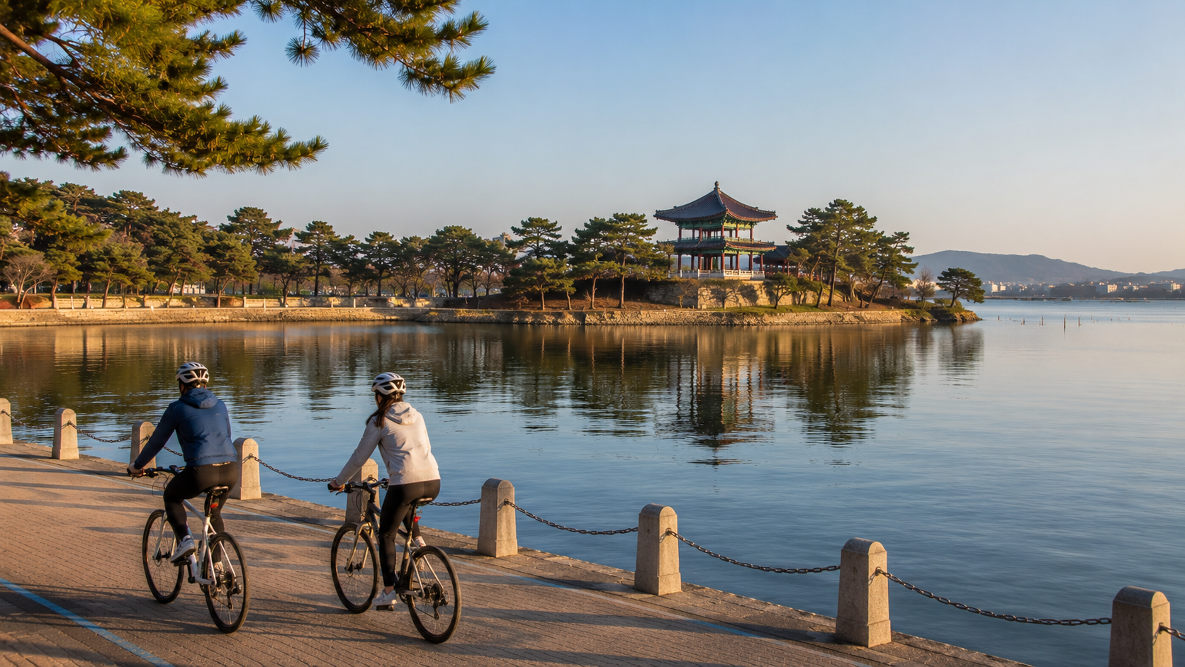 Morning cyclists beside Gyeongpo Lake with Gyeongpodae Pavilion and pine trees in the distance