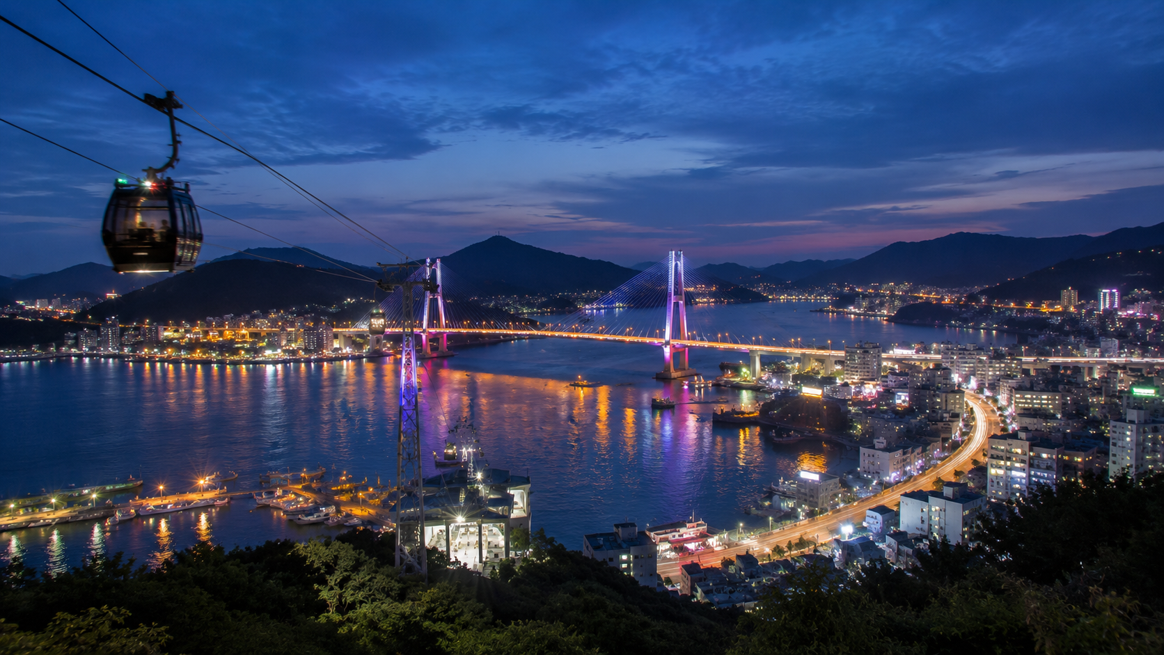 Yeosu harbor at blue hour, viewed from above with cable-car cabins and illuminated Dolsan Bridge