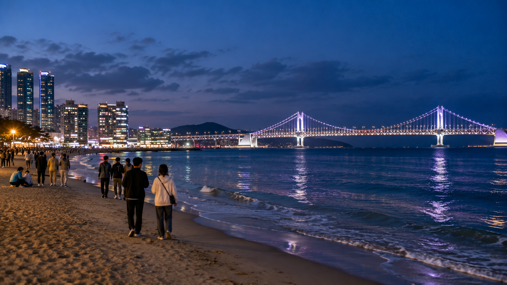 Evening at Gwangalli Beach with people walking along the shore and Gwangandaegyo Bridge illuminated across the water