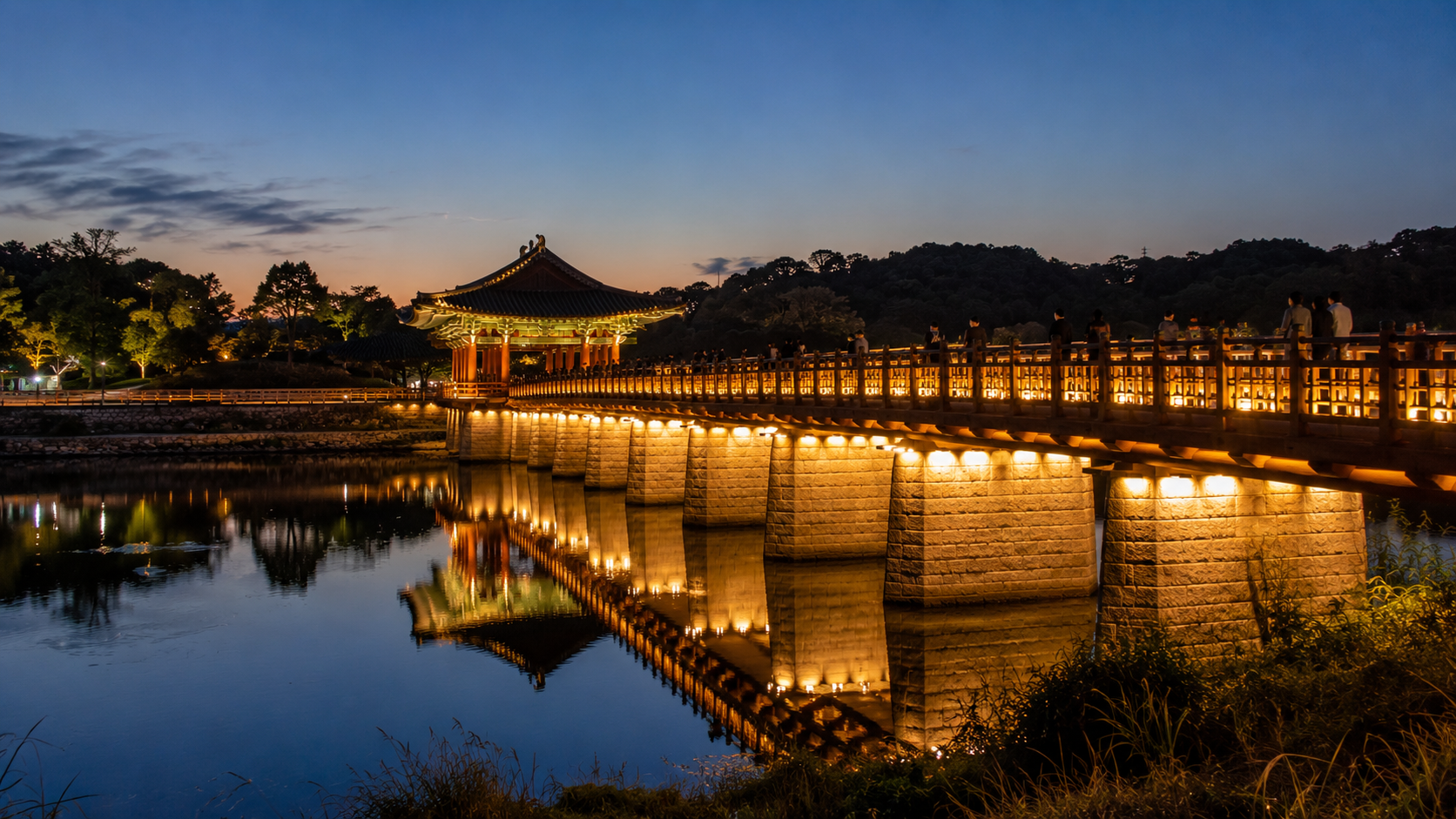 Wolyeonggyo Bridge illuminated after sunset with visitors walking across the wooden deck
